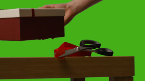 Nahaufnahme-Eines-Mannes,-Der-Verpackte-Geschenke-In-Mit-Bändern-Dekorierten-Schachteln-Auf-Einem-Tisch-Ablegt,-Aufgenommen-Vor-Einem-Greenscreen